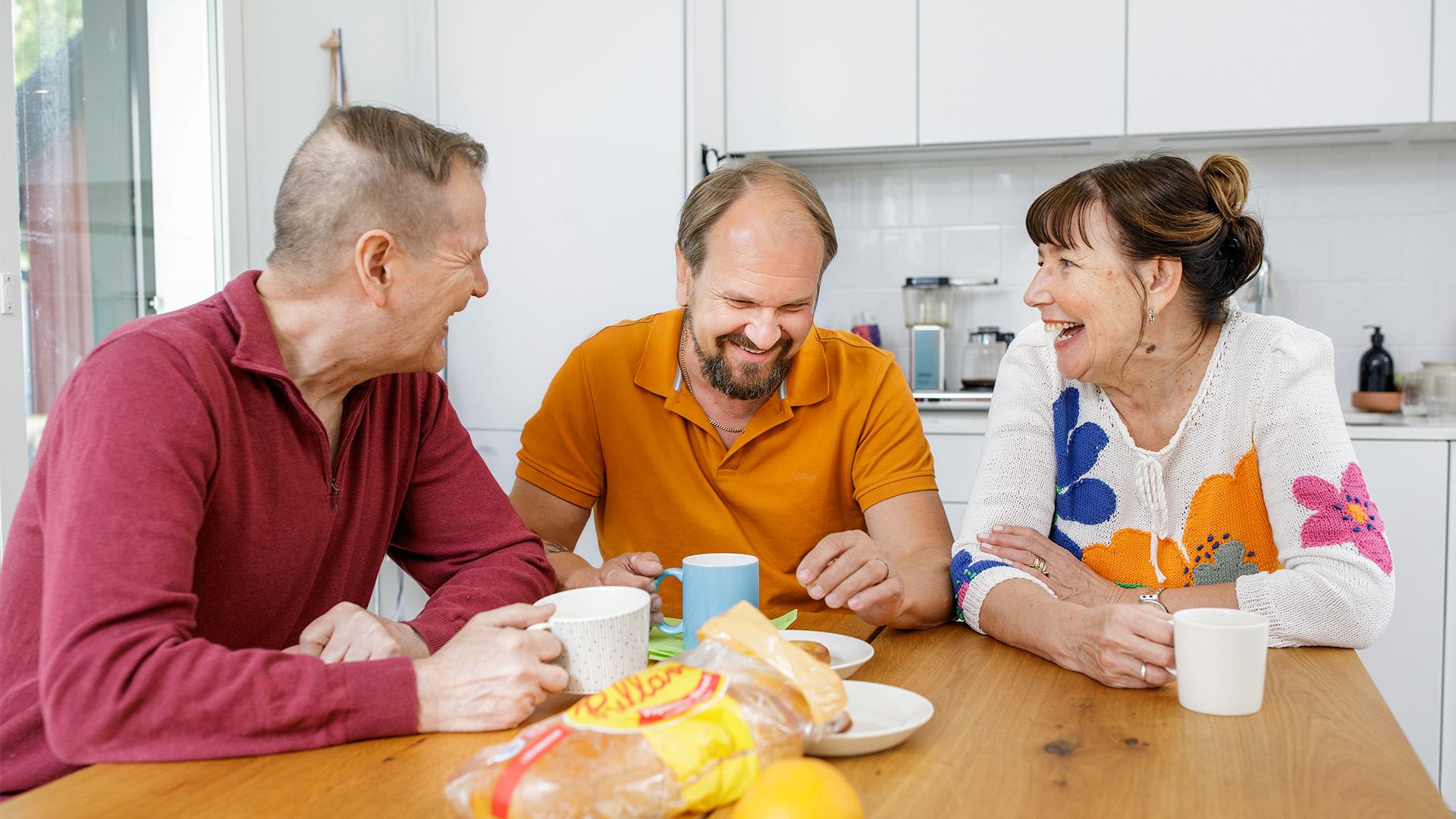 Aikuinen lapsi vanhempiensa kanssa kahvilla