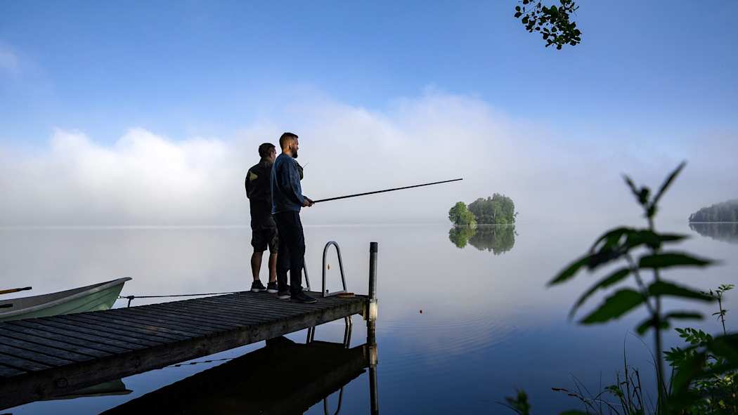 Kaksi miestä ongella mökkilaiturilta