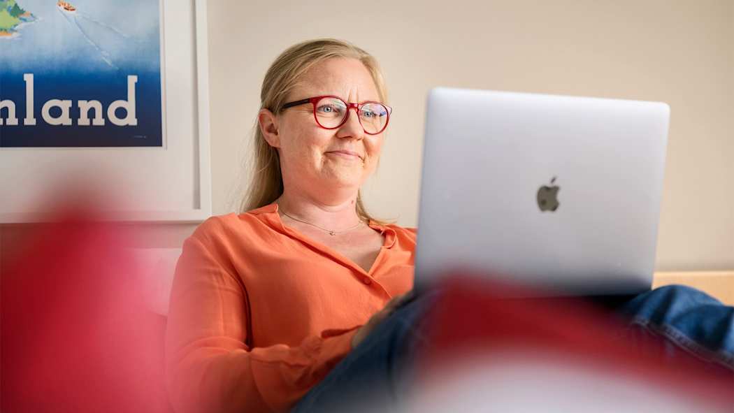 Nainen sohvalla työskentelemässä tietokoneella