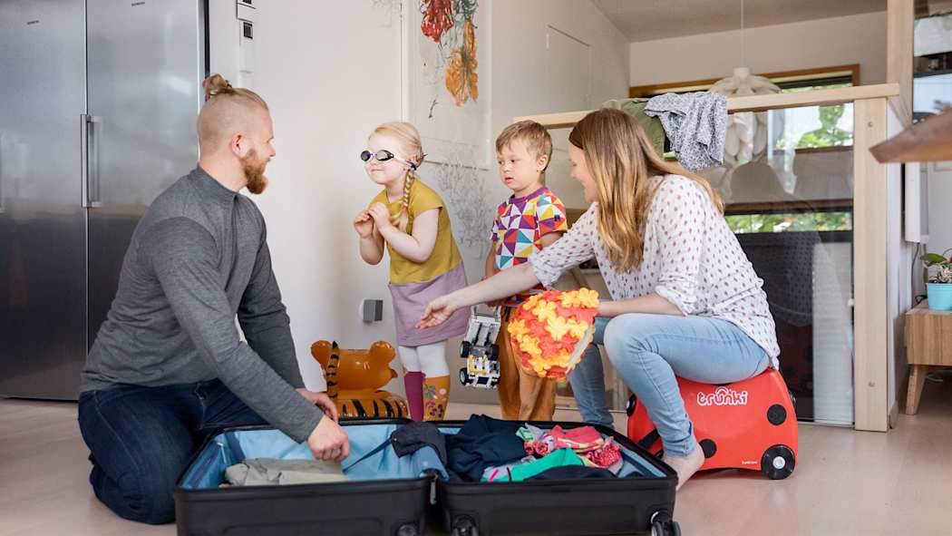 Vanhemmat ja kaksi lasta pakkaamassa matkalaukkua