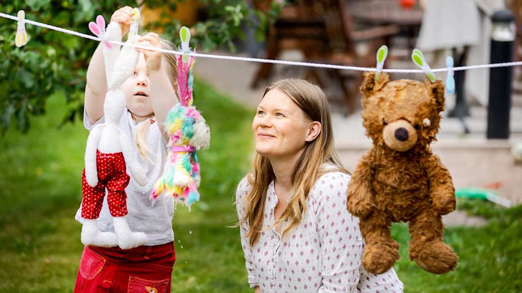 Äiti ja lapsi laittavat pehmolelupyykkiä kuivumaan