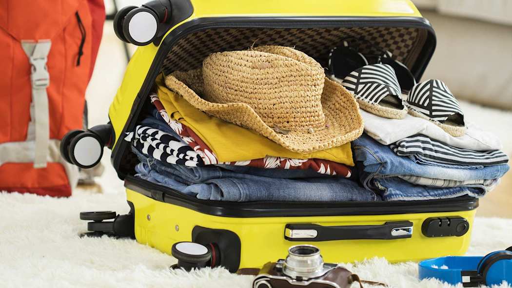 Täyteen pakattu avonainen keltainen matkalaukku