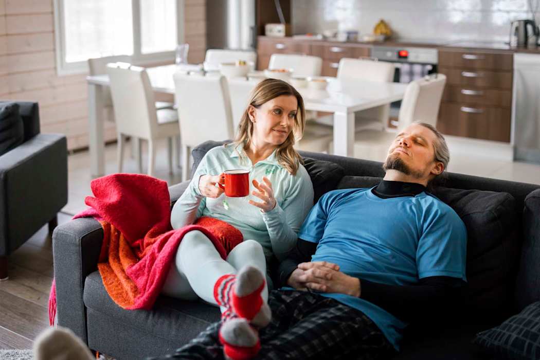 Pariskunta istuu sohvalla. Naisella on kuppi kädessä ja miehellä on silmät kiinni.