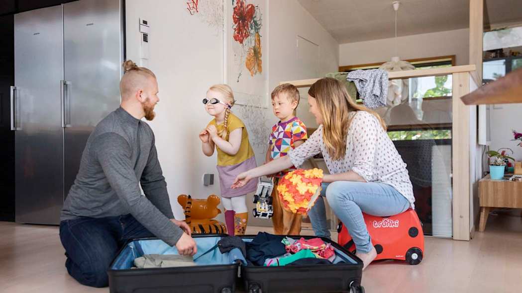 Äiti, isä ja kaksi lasta pakkaavat maktalaukkua