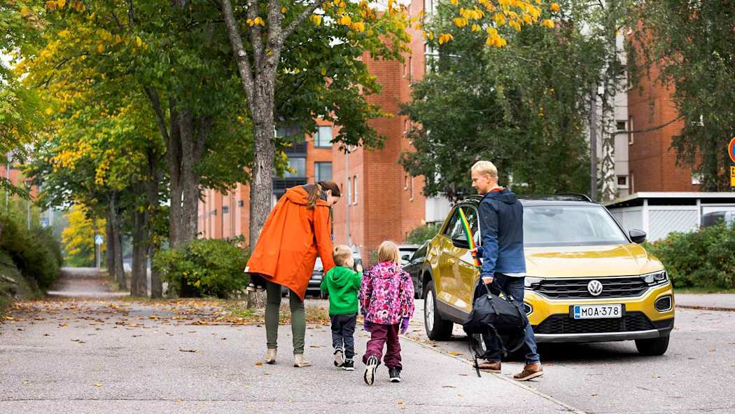 Nelihenkinen perhe menossa kohti autoa syyssäässä