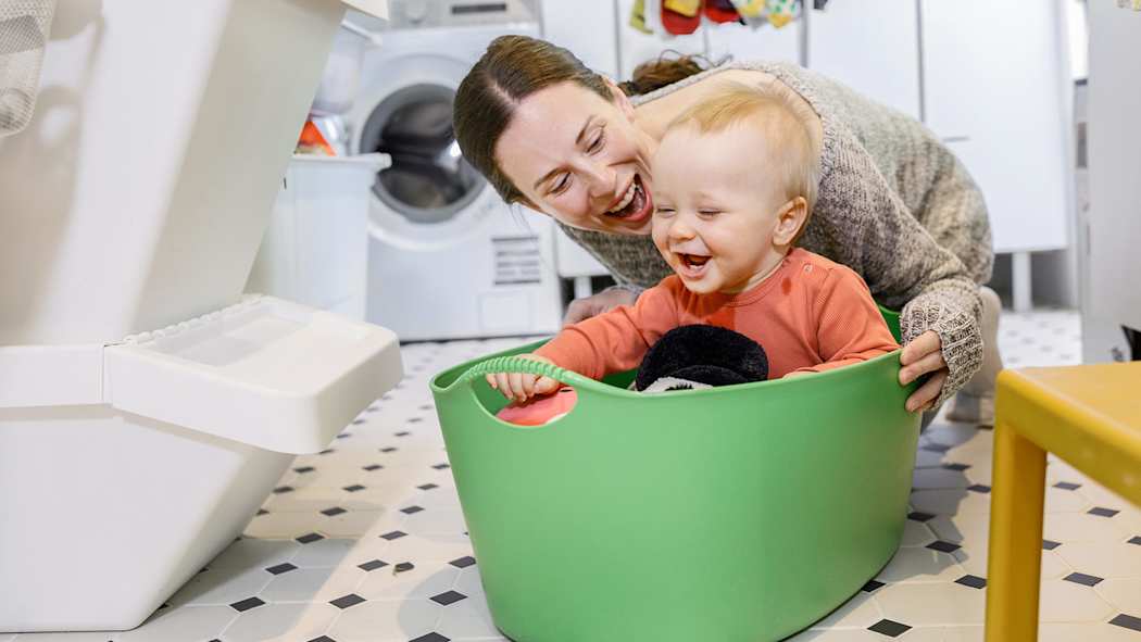 Äiti ja vauva istuvat lattialla nauraen