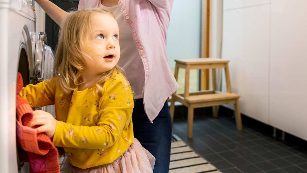 Lapsi auttamassa äitiään pyykinpesussa