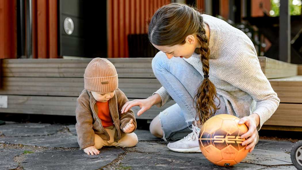 Äiti leikkii vauvan kanssa pihalla