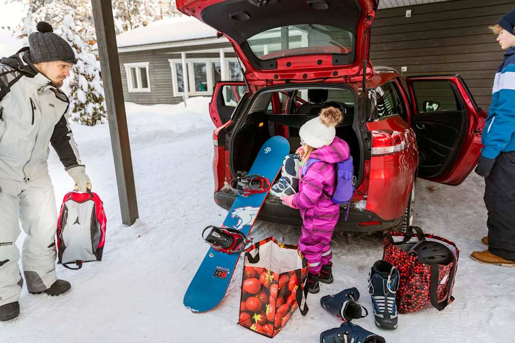 Isä ja lapsi pakkaamassa tavaroita auton takakonttiin