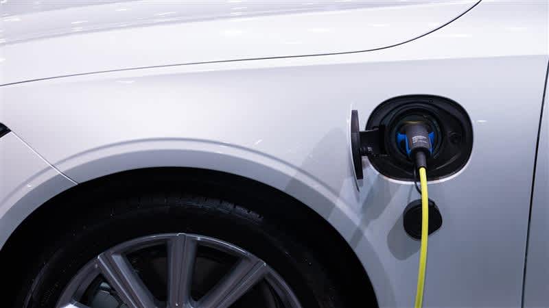 Lähikuva valkoisesta sähköautosta, joka on laturissa.