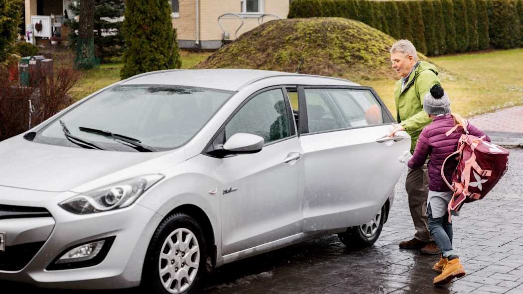 Lapsi nousemassa isoisän audon kyytiin ensilumen leijaillessa