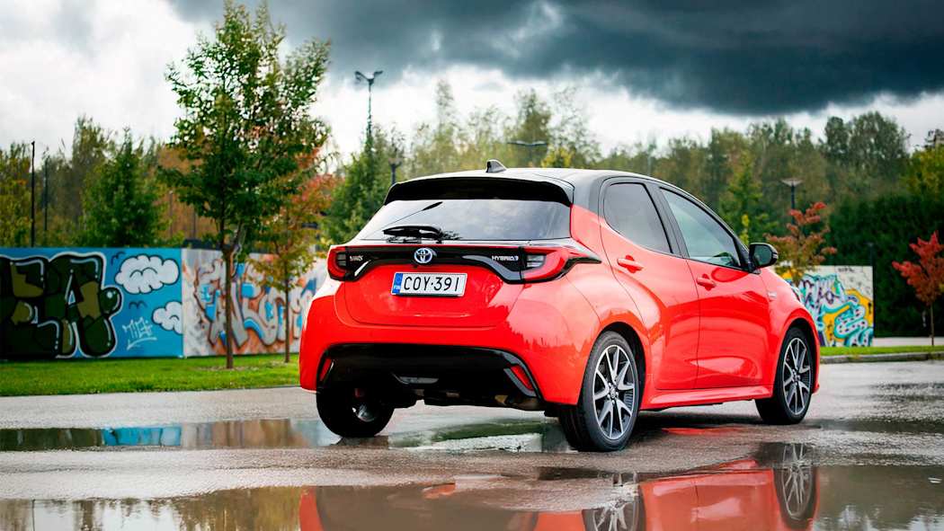 Punainen henkilöauto parkkipaikalla sadesäällä