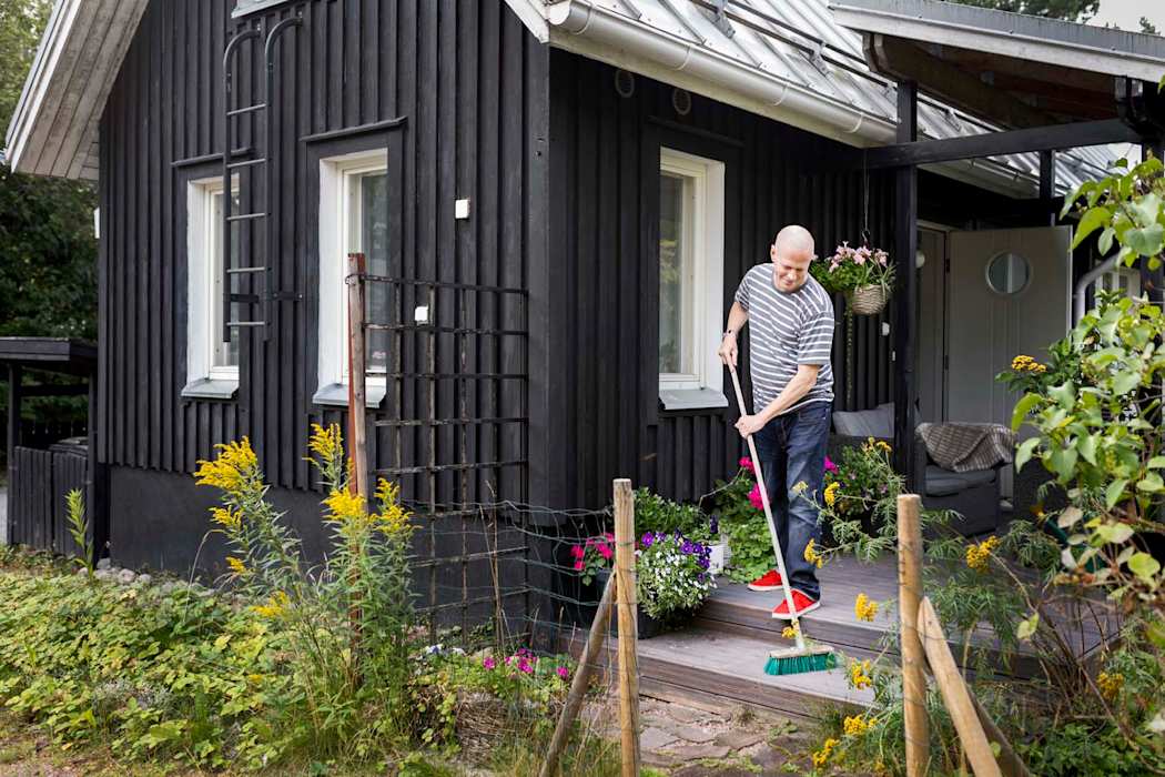 Mies lakaisee terassia omakotitalon edustalla.